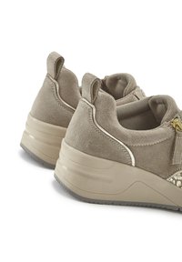 Beige Slipper mit Wildledertextur, goldenen Hardware-Akzenten und einem gepolsterten Kragen. Dicke Gummisohle für Stabilität und Komfort.