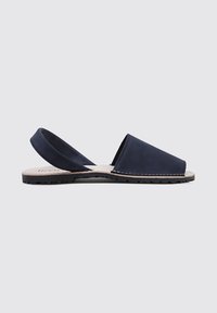Sandalia de piel azul marino con tacón abierto, suela plana, punta abierta y un simple detalle de costura a lo largo de los bordes. Textura suave, diseño minimalista.