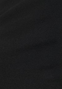 Svart ribbat tyg visar vertikala linjer och en jämn textur, lämplig för kläder, utan synliga mönster eller detaljer.