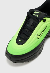 Nike Air Max sportbačiai, turintys neoninės žalios spalvos tinklinį viršų su juodais akcentais, bangos formos dizainu ir standartiniu raištelių sistemos uždarymu. Juodas guminis padas.