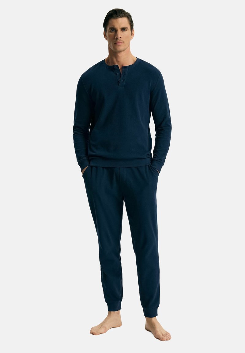 Granatowy bawełniany zestaw odzieży domowej z długim rękawem, składający się z bluzki henley z detalami guzików oraz dopasowanych spodni o zwężanym kroju z elastycznymi mankietami.