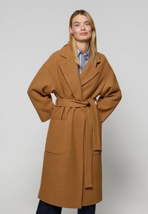 Camel-kleurige wikkeljas van zachte stof, met een brede revers, lange mouwen, een strikceintuur in de taille en twee grote voorzakken.