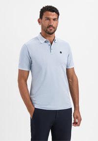 Lichtblauwe polo met een twee-knopen sluiting, korte mouwen en een klein logo op de borst. Gemaakt van een gladde stof.