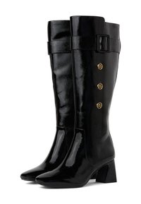 Fekete, térd fölé érő csizmák fényes lakkbőrből, hegyes orral, tömör sarokkal és aranyszínű díszgombokkal.