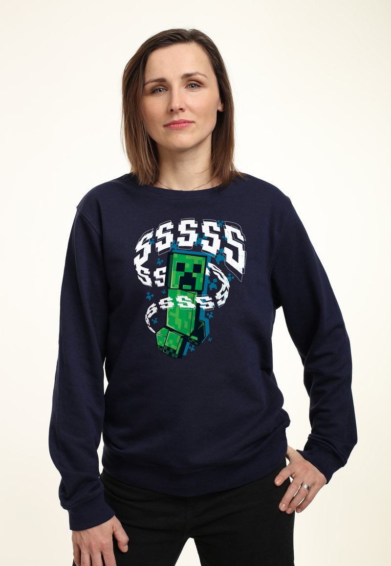 Sudadera azul marino con un gráfico de un personaje pixelado en verde. Mangas largas, cuello redondo, tela suave, con acentos en blanco y azul agua.