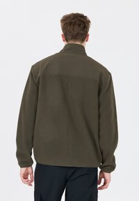 Olivgrön fleecejacka med hög krage, texturerat tyg och kontrasterande slät axelpanel, stilren med långa ärmar och avslappnad passform.