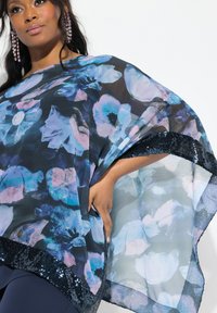 Kimono fluido in tessuto nero trasparente con stampa floreale in blu e rosa. Presenta un orlo rifinito con paillettes e una vestibilità ampia e confortevole.