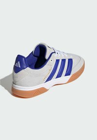 Grey suede sneaker with blue accents, three blue stripes, a padded collar, white laces, and a gum rubber sole. Text reads "SPECIALIST."