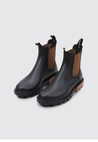 Bottes noires en caoutchouc à cheville avec des panneaux élastiques côtelés marron, semelles texturées et languettes de tirage, présentant un design robuste et un ajustement confortable.