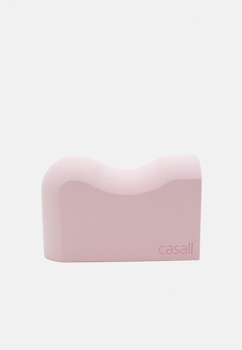 Pink foam yoga block with a curved top shape, smooth texture, and rounded edges. Features embossed brand name "casall" on one side.