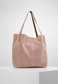 Tygväska i mjuk rosa mocka med två kontrasterande bruna läderremmar. Har en rundad topp och vertikala sömnadsdetaljer.