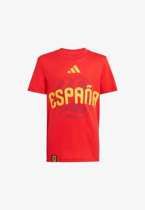 Crvena sportska majica s kratkim rukavima sa žutim tekstom "España", Adidas logom iznad i suptilnim tamnim grafičkim prikazom nogometne lopte iza teksta.