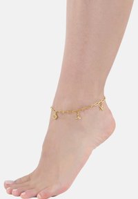 Tobillera de oro hecha de cadenas enlazadas con charms de concha, cola de ballena y estrella de mar. El diseño es delicado con un acabado brillante.