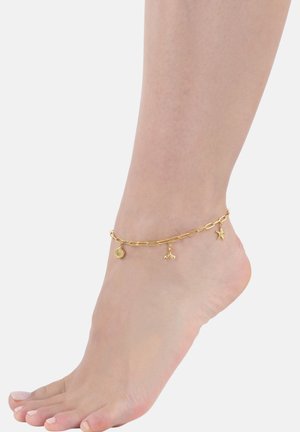 Gouden enkelband gemaakt van gekoppelde kettingen met schelp-, walvissenstaart- en zeesterrencharms. Het ontwerp is delicaat met een glanzende afwerking.