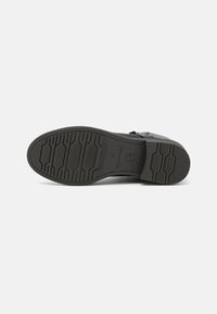 Semelle d'une botte noire avec une bande de roulement à motifs, talon bloc, taille 37, avec le logo Tom Tailor sur fond blanc.