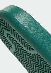 Zelený textúrovaný materiál s podrážkou s vzorom v tvare cikcakových drážok; okraj zaoblený a hladký pre ergonomický tvar.