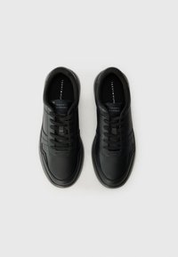 Zapatillas de cuero negro con punta redonda, diseño de cordones, acentos perforados y suela de goma texturizada. Logo visible en la plantilla.