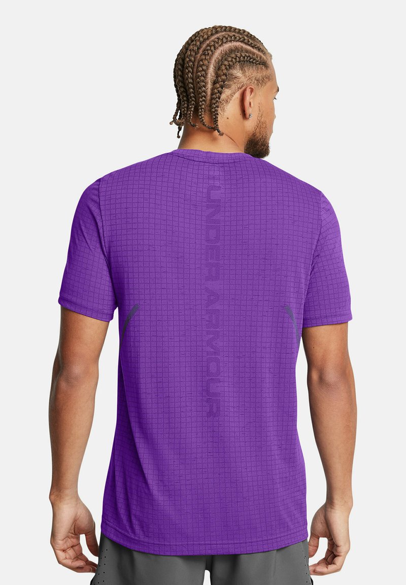 Lilla lühikese varrukaga särk, millel on ruuduline muster, ning esipoolt rõhutab seljaosas vertikaalselt paiknev silmatorkav "Under Armour" logo ja hallid aksessuaarid.