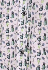 Motif de cocktails tropicaux, ananas et feuilles sur un tissu clair avec des boutons noirs au centre.
