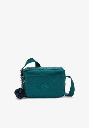 Teal crossbody bag made of durable fabric, featuring a zip closure, front pocket, logo patch, and a detachable monkey keychain.
