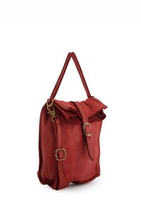 Red leather bag with a textured finish, fold-over flap, braided strap, and brass hardware. Compact square shape with visible stitching details.