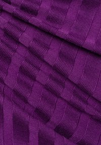 Strukturierter lila Stoff mit einem wellenförmigen Muster, das abwechselnd gerippte und glatte Abschnitte zeigt, und eine reiche, tiefe Farbtönung sowie eine weiche Textur präsentiert.