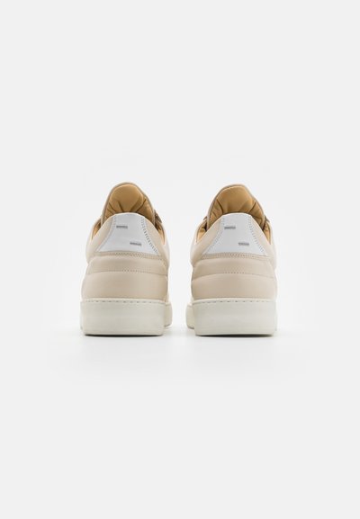 Beige bőr sportcipők párnázott világosbarna béléssel és fehér gumitalppal, minimalista dizájnnal és diszkrét márkázással a saroknál.