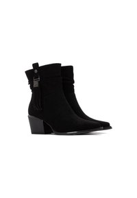 Botines de ante negro con un diseño arrugado, punta afilada y un tacón bajo y ancho. Presenta un borlas decorativas y un acento metálico.