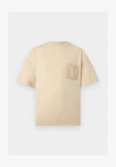 Μπεζ κοντομάνικο μπλουζάκι με στρογγυλή λαιμόκοψη και υφασμένη πλεκτή τετράγωνη τσέπη στο αριστερό στήθος.