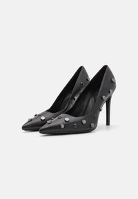 Escarpins noirs en cuir à bout pointu, ornés de clous métalliques et d'accents sur les côtés. Talons stilettos et texture lisse.