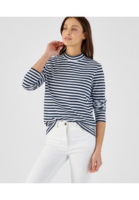 Marineblauw en witte gestreepte langemouwtop met een hoge hals; gecombineerd met witte high-waisted jeans, met een ontspannen pasvorm en zachte stof.