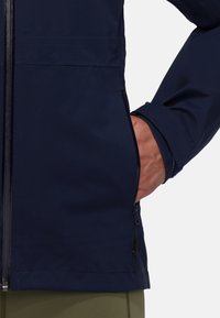 Navy waterproof jacket with a zippered front, adjustable cuffs, side seam pockets, and a smooth, matte texture.