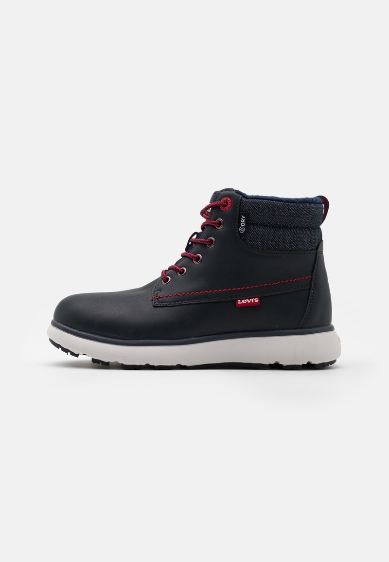 Bottine en cuir noir avec semelle blanche, lacets rouges, couture rouge, col en denim et petite étiquette rouge Levi's sur le côté.
