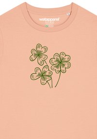 Lichtperzikwite T-shirt van katoen, met een groen bloemmotief en drie gestileerde klavers op de voorkant.