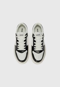 Sneaker bianco e nero con tomaia in pelle liscia, punta perforata e dettagli testurizzati. Presenta lacci bianchi e linguetta con logo.