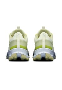 Baskets de sport jaune clair avec des tiges en maille, semelles gris foncé et accents vert fluo au niveau du talon, dotées d'une languette pour un enfilage facile.