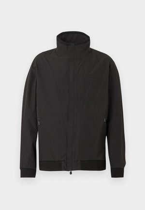 Giacca nera con zip e maniche lunghe, colletto alto, tasche laterali con zip e logo frontale sottile sul lato sinistro del petto.