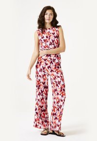 Kleurvolle bloemenjumpsuit van lichtgewicht stof met brede benen, in tinten van rood, roze en wit. Inclusief een mouwloos ontwerp en een riem.