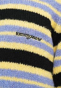 Pull en tricot avec des rayures horizontales noires, jaunes et bleu clair. Logo "tommyjeans" brodé en noir sur le côté.