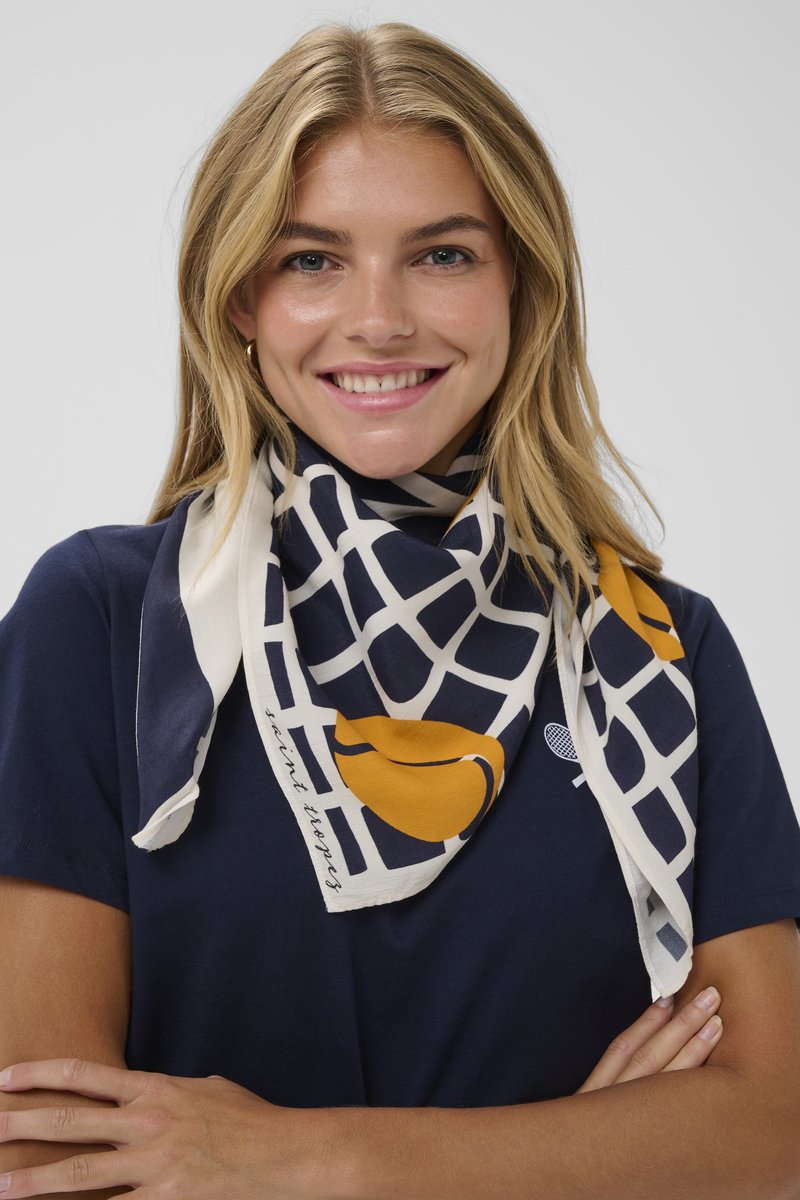 Rakstainais šalle ar tumši zilu režģa dizainu un dzelteniem akcentiem, izgatavota no mīksta auduma, nosvērta ap kaklu. Malā esošais teksts lasāms "saint tropez."