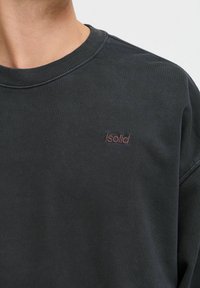 Tumehall ridaseelne dressipluus, millel on soonikuga kaelus ja väike burgundia värvi "Isolid" logo rinnal. Pehme, tekstuuriga kangas.