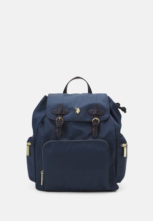 Marineblauer Rucksack mit vorderer Reißverschlusstasche, zwei seitlichen Reißverschlusstaschen, dunkelbraunen Leder-Riemen mit Schnallen, Tragegriff oben und kleinem goldenem Pferdelogo auf der Klappe.