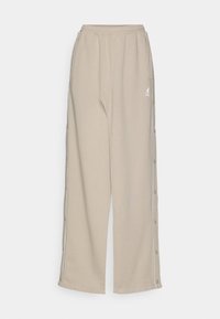 Beige sweatpants made of soft fabric, featuring a relaxed fit, side snap buttons, and front pockets with a small logo on the hip.