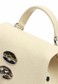 Borsa in pelle di colore crema con chiusure ovali in argento e manico superiore curvo collegato da anelli metallici.