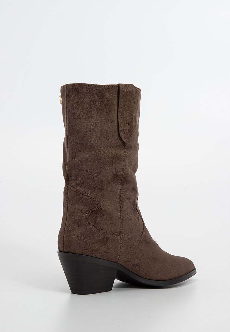 Stivale da cowboy in suede marrone con punta leggermente appuntita, tacco impilato e cuciture decorative sul gambale. Dettaglio con zip laterale.