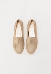 Beige semskede mokkasin-sko med en glatt tekstur, avrundet tå og et dekorativt sydd bånd over forsiden. Flat såle, uten hæl.