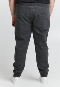 Szürke melegítőnadrág puha, texturált anyagból, elasztikus derékpánttal és szegélyekkel. Két hátsó zsebbel és laza szabással rendelkezik.