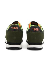 Pár zeleno-čiernych tenisiek s oranžovým textom "1968" na päte, neonovo zeleným interiérom a bielo-čiernymi podrážkami, zobrazených zozadu.