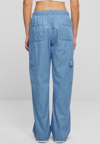 Modré džínové kalhoty typu cargo s elastickým pasem, širokými nohavicemi a dvěma zadními kapsami. Látka má hladkou texturu a ležérní design.