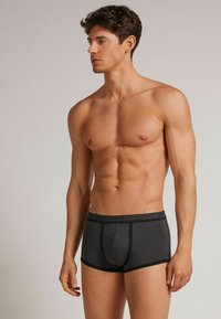 Šedé boxerky s kontrastním černým pasem. Hladká tkanina, přiléhavý design a kontury na švech. Žádné viditelné vzory nebo kovové prvky.